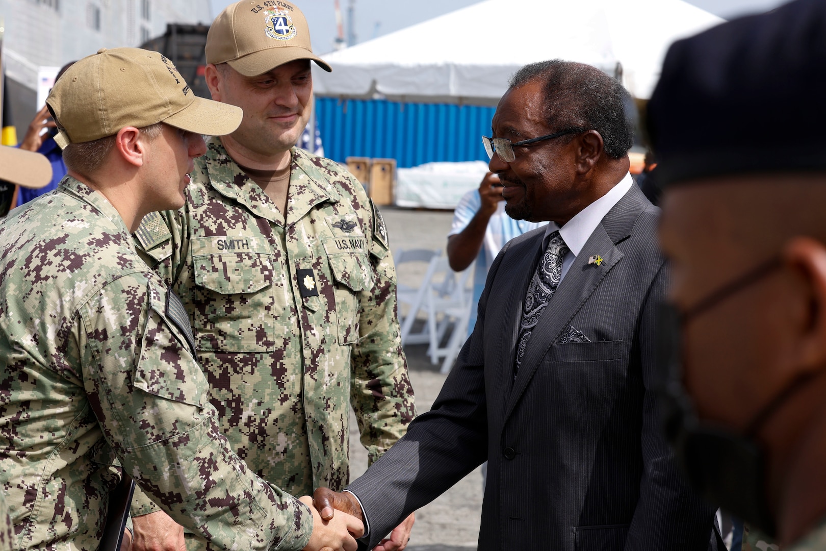 Lt. Cmdr. Zachary Smith, Continuing Promise 2024 Mission Commander, and Lt. Daniel Ehrlich, Continuing Promise 2024 Public Affairs Officer, greet U.S. Ambassador to Jamaica N. Nick Perry prior to his visit and tour of Spearhead-class expeditionary fast transport ship USNS Burlington (T-EPF 10) at Kingston Wharves.