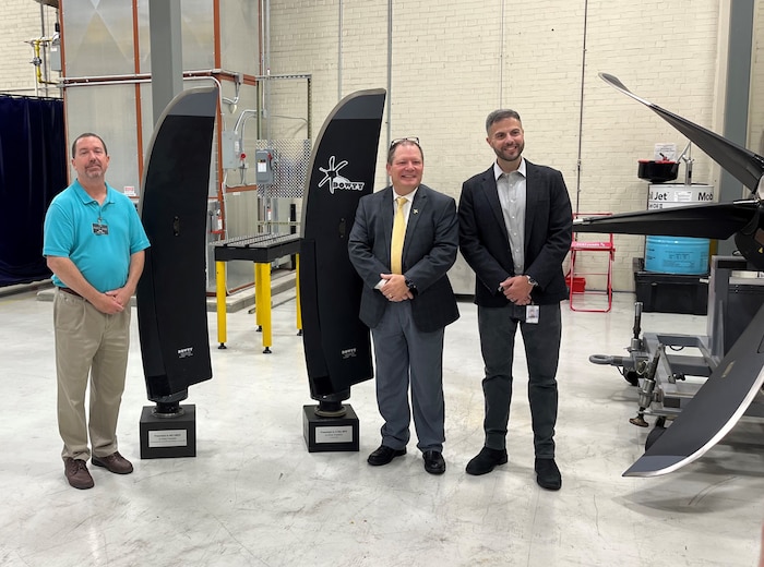 group of people standing next to aircraft propeller
