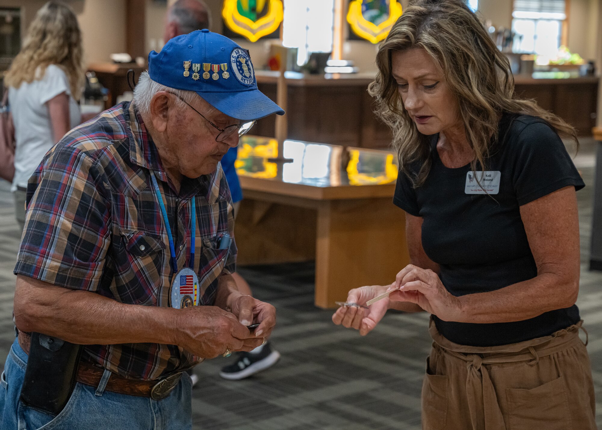 Kelly Weiand, North Dakota Military Outreach Program military outreach specialist (right), provides resources to Freddie Rios, a military retiree, during Retiree Appreciation Day at Minot Air Force Base, North Dakota, July 12, 2024. A number of agencies attended Retiree Appreciation Day to provide support to military retirees. (U.S. Air Force photo by Senior Airman Kyle Wilson)