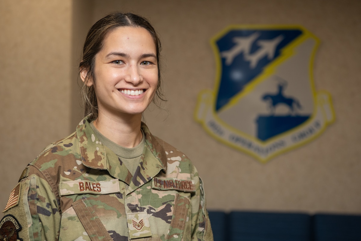 Airman standing in front of 192nd Operations Group emblem.