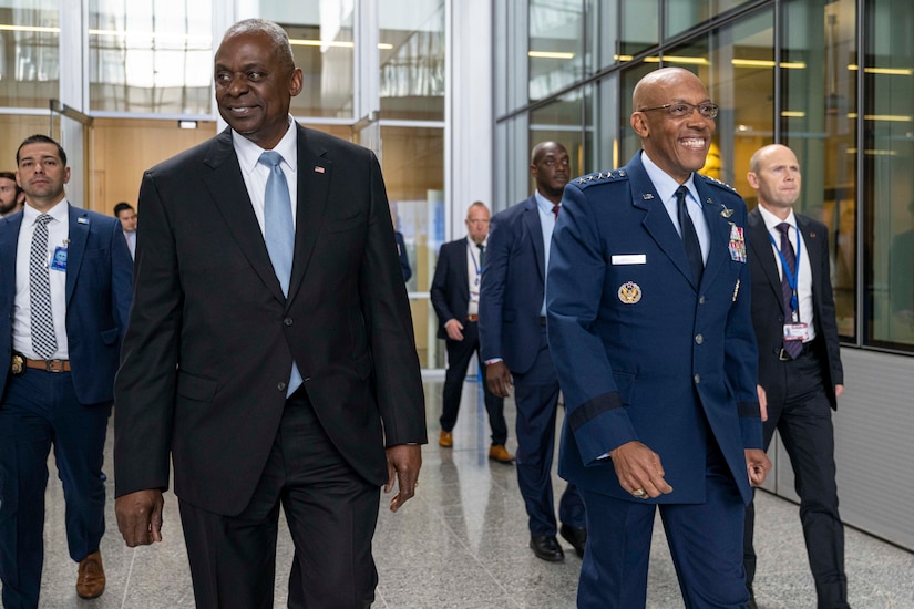 Two men, one in civilian attire and the other in uniform, walk along a hallway.