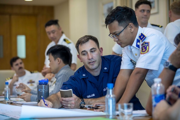 240709-N-SF508-1295 CAM RANH INTERNATIONAL PORT, Vietnam (July 9, 2024) – Cmdr. Charles England, center, executive officer, U.S. Coast Guard Legend-class cutter USCGC Waesche (WMSL 751), speaks with a member of the Vietnam Coast Guard as part of a joint U.S. – Vietnam subject matter expert exchange between members of the U.S. Coast Guard, U.S. 7th Fleet, and Vietnamese Navy and Coast Guard during a port visit by Waesche and the U.S. 7th Fleet flagship USS Blue Ridge (LCC 19), in Cam Ranh, Vietnam, July 9, 2024. U.S. 7th Fleet is the U.S. Navy's largest forward-deployed numbered fleet, and routinely interacts and operates with allies and partners in preserving a free and open Indo-Pacific region. (U.S. Navy photo by Mass Communication Specialist 1st Class Charles Oki)