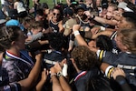 Wearing a pink ribbon in her hair, Navy Ensign Megan Neyen  leads a huddle of rugby players from all services in a cheer  ‘For Those Who Can’t’ at the conclusion of the 2024 Armed Forces Women’s Rugby Championships in San Diego, Calif. July 13, 2024. Team Army wore the motto “For Those Who Can’t’ on their uniforms to honor injured or deceased female service members. (DoD photo by EJ Hersom)