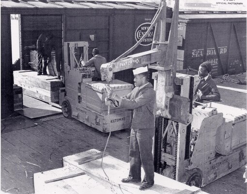 [Black stevedores unloading ordnance and ammunition from a boxcar to the pier. Image courtesy National Park Service]