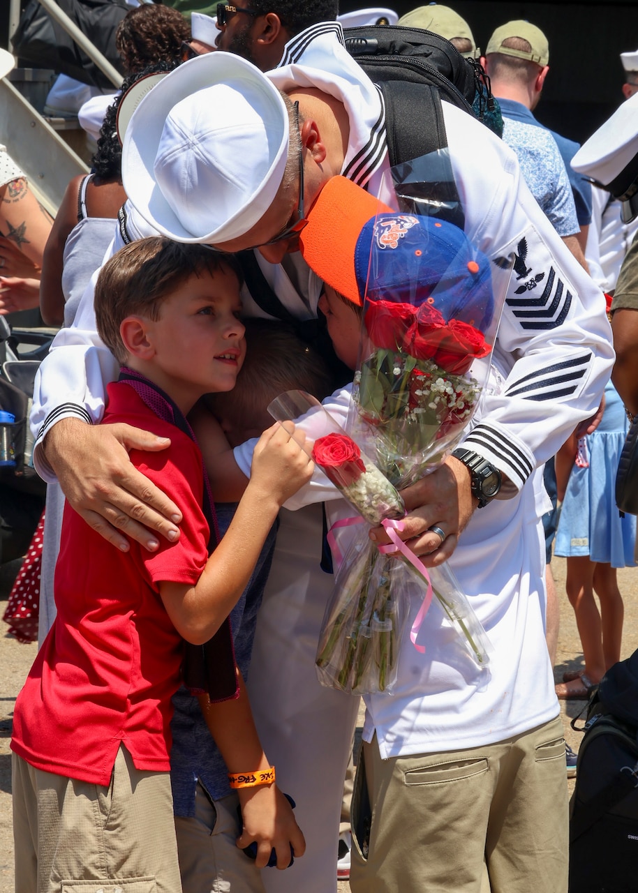 Aviation Boatswain's Mate (Aircraft Handling) 1st Class Ryan Oney, from Cleveland, Ohio, assigned to the Nimitz-class aircraft carrier USS Dwight D. Eisenhower (CVN 69), embraces his kids after a nine-month deployment to the Atlantic.