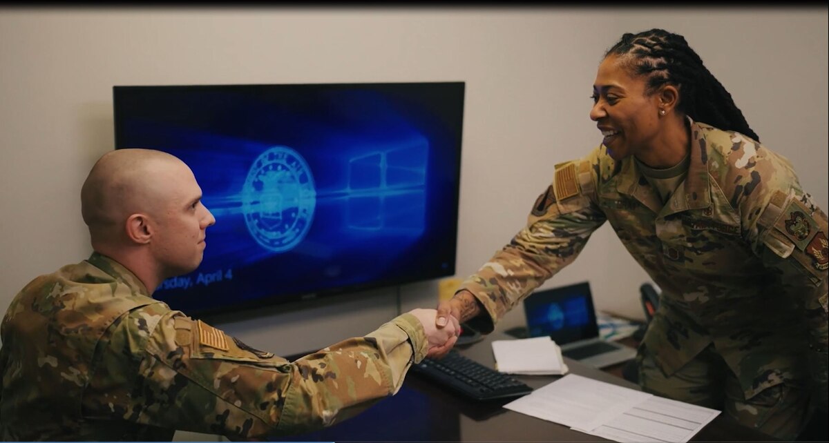 A man and woman in Air Force occupational uniforms shake hands.