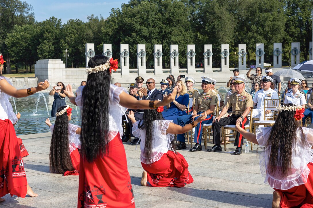 Dancers perform in front of seated service members at a memorial.