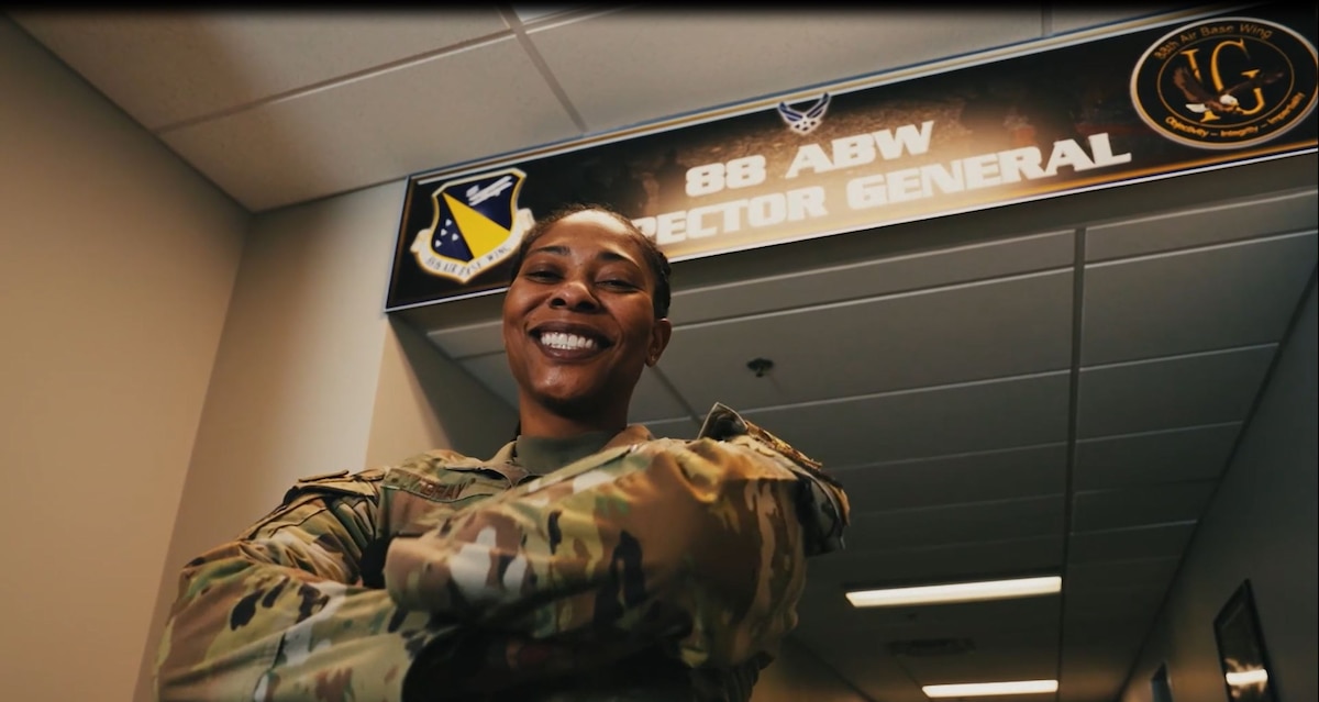 A woman wearing an Air Force occupational uniform poses for a photo with her arms crossed.