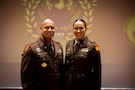 man and woman wearing U.S. Army uniforms pose for a photo.