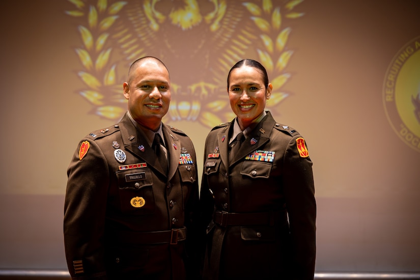 man and woman wearing U.S. Army uniforms pose for a photo.