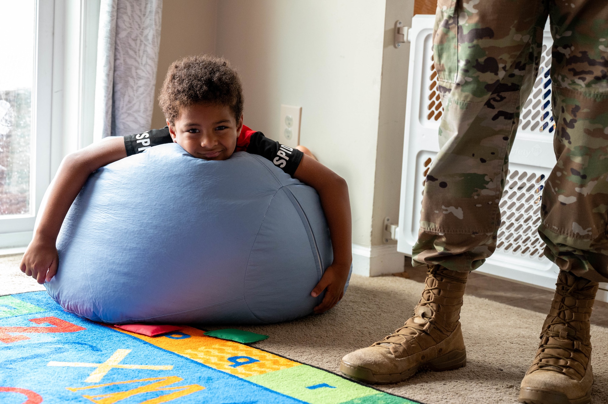 Kameron Cox, son of Krista Cox, rests on a bean bag chair while his mother gives a home tour to U.S. Air Force Col. Ryan A. F. Crowley, commander of Joint Base Anacostia-Bolling and the 11th Wing, following the opening of the newest Family Child Care home at JBAB, Washington, D.C., July 10, 2024. One of the incentives of the Family Child Care Home program is that providers could be eligible to get paid for taking care of their own children. (U.S. Air Force photo by Hayden Hallman)