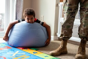 Kameron Cox, son of Krista Cox, rests on a bean bag chair while his mother gives a home tour to U.S. Air Force Col. Ryan A. F. Crowley, commander of Joint Base Anacostia-Bolling and the 11th Wing, following the opening of the newest Family Child Care home at JBAB, Washington, D.C., July 10, 2024. One of the incentives of the Family Child Care Home program is that providers could be eligible to get paid for taking care of their own children. (U.S. Air Force photo by Hayden Hallman)