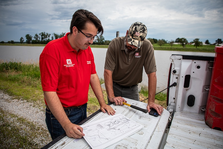 Isaiah Rubio, left, and Curtis Miller, hydraulic engineers with the U.S. Army Corps of Engineers, Omaha District, prepare to set a staff gage along a levee in Papillion Creek, Nebraska, June 28, 2024. They will use the staff gage to measure water surface elevation as a precautionary measure against flood waters in June 2024 from the Missouri River. Nine USACE levee surveillance teams went onsite to levee locations and engaged with levee sponsors, state, tribal and emergency management officials to continue to monitor river conditions. (U.S. Army photo by Declan Barnes)