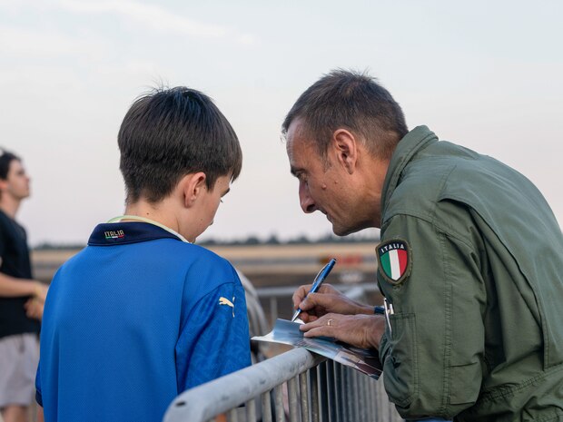 An aeronautical militare pilot signs an autograph for a young spectator during the Frecce Tricolori’s performance at the 18th annual California Capital Airshow at Mather Airport, California, July 13, 2024.