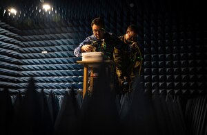 Two men work in a room designed to test sound and radio waves.