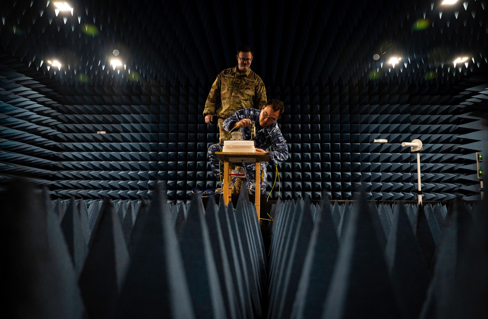 Two men work in a room designed to test sound and radio waves.