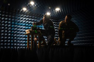 Two men work in a room designed to test sound and radio waves.