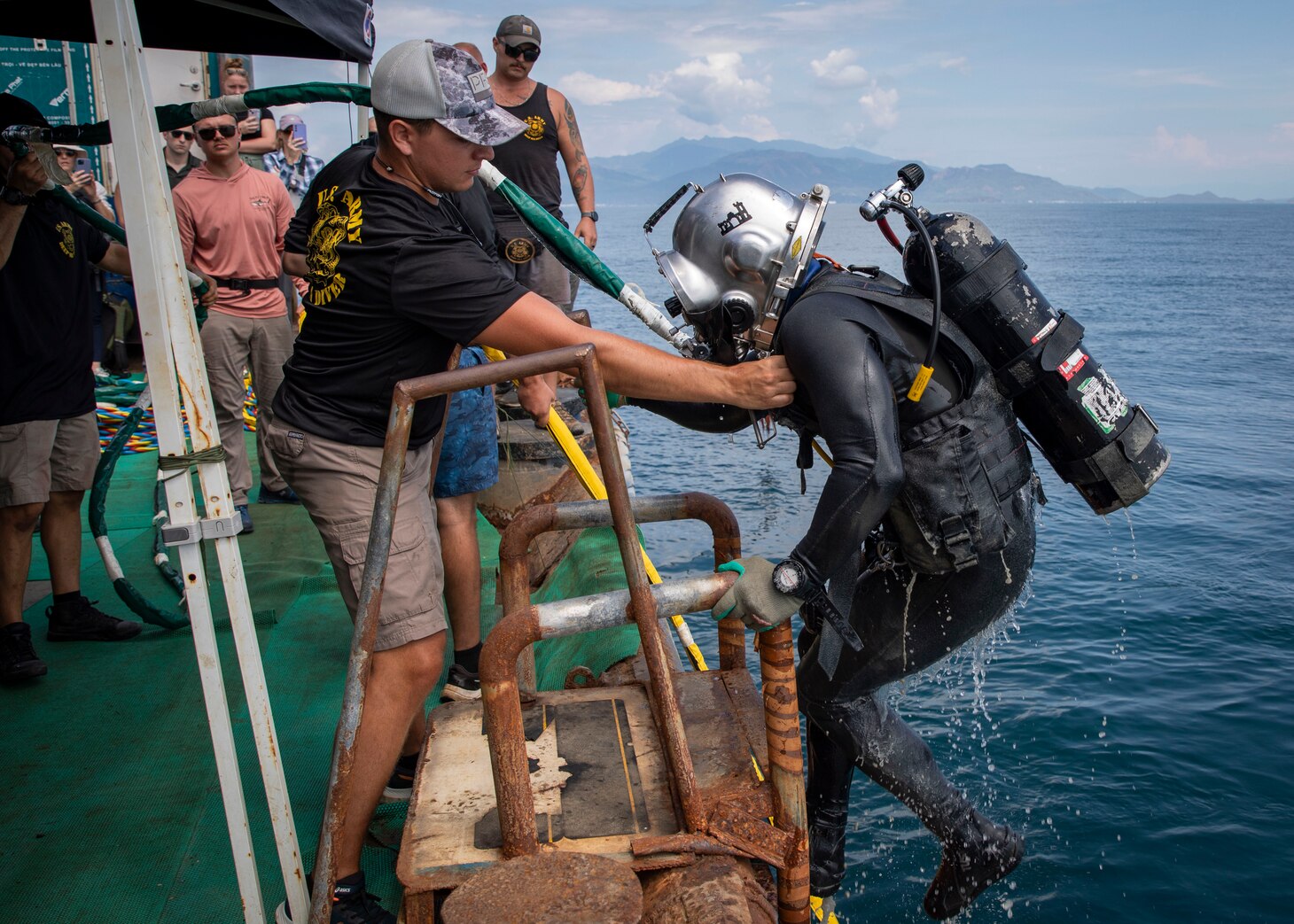 240709-N-WM182-1056 NHA TRANG, Vietnam (July 9, 2024) U.S. Army Sgt. Devin Rhodes, a deep sea diver assigned to the Defense POW/MIA Accounting Agency (DPAA), exits the water aboard a dive barge supporting the DPAA investigation of a 1971 helicopter crash site in the Bay of Nha Trang July 9. U.S. 7th Fleet is the U.S. Navy's largest forward-deployed numbered fleet, and routinely interacts and operates with allies and partners in preserving a free and open Indo-Pacific region. (U.S. Navy Photo by Mass Communication Specialist 2nd Class Caitlin Flynn)