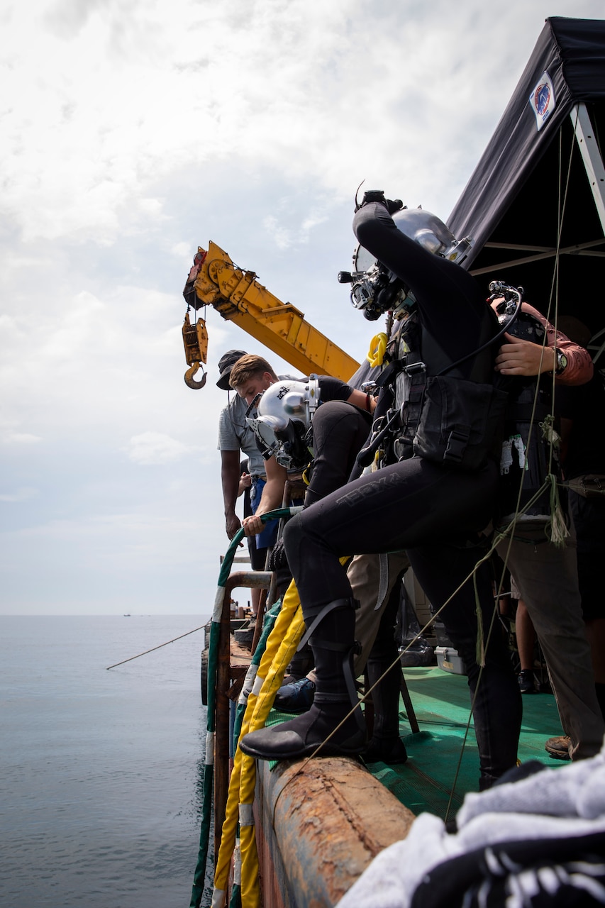 240709-N-WM182-1086 NHA TRANG, Vietnam (July 9, 2024) Deep sea divers assigned to the Defense POW/MIA Accounting Agency (DPAA) prepare to enter the water aboard a dive barge supporting the DPAA investigation of a 1971 helicopter crash site in the Bay of Nha Trang July 9. U.S. 7th Fleet is the U.S. Navy's largest forward-deployed numbered fleet, and routinely interacts and operates with allies and partners in preserving a free and open Indo-Pacific region. (U.S. Navy Photo by Mass Communication Specialist 2nd Class Caitlin Flynn)