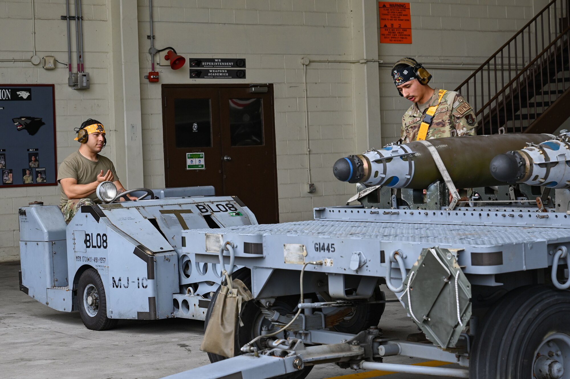 Senior Airman Nicholas Velazquez, left, and Senior Airman Jacob Garcia, 80th Fighter Generation Squadron weapons load crew members, coordinate to load munitions during the 2024 2nd Quarter Dedicated Crew Chief and Load Crew Competition.