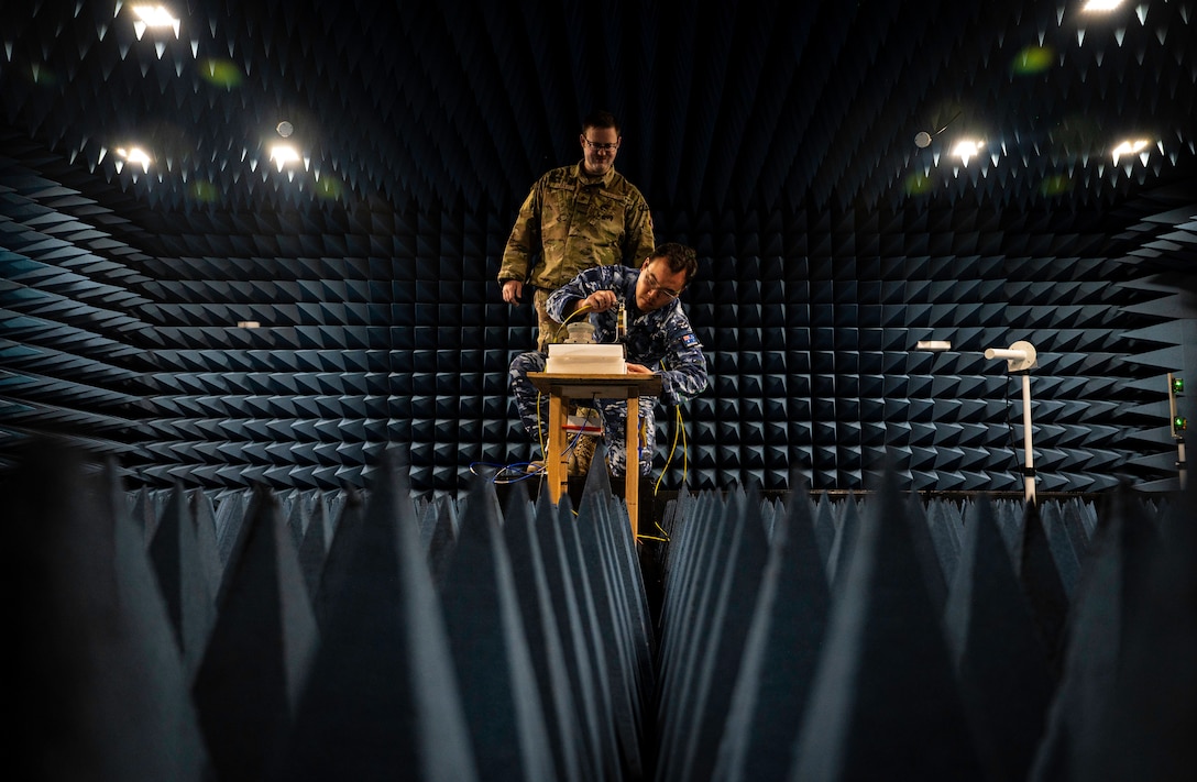 Two men work in a room designed to rest sound and radio waves.