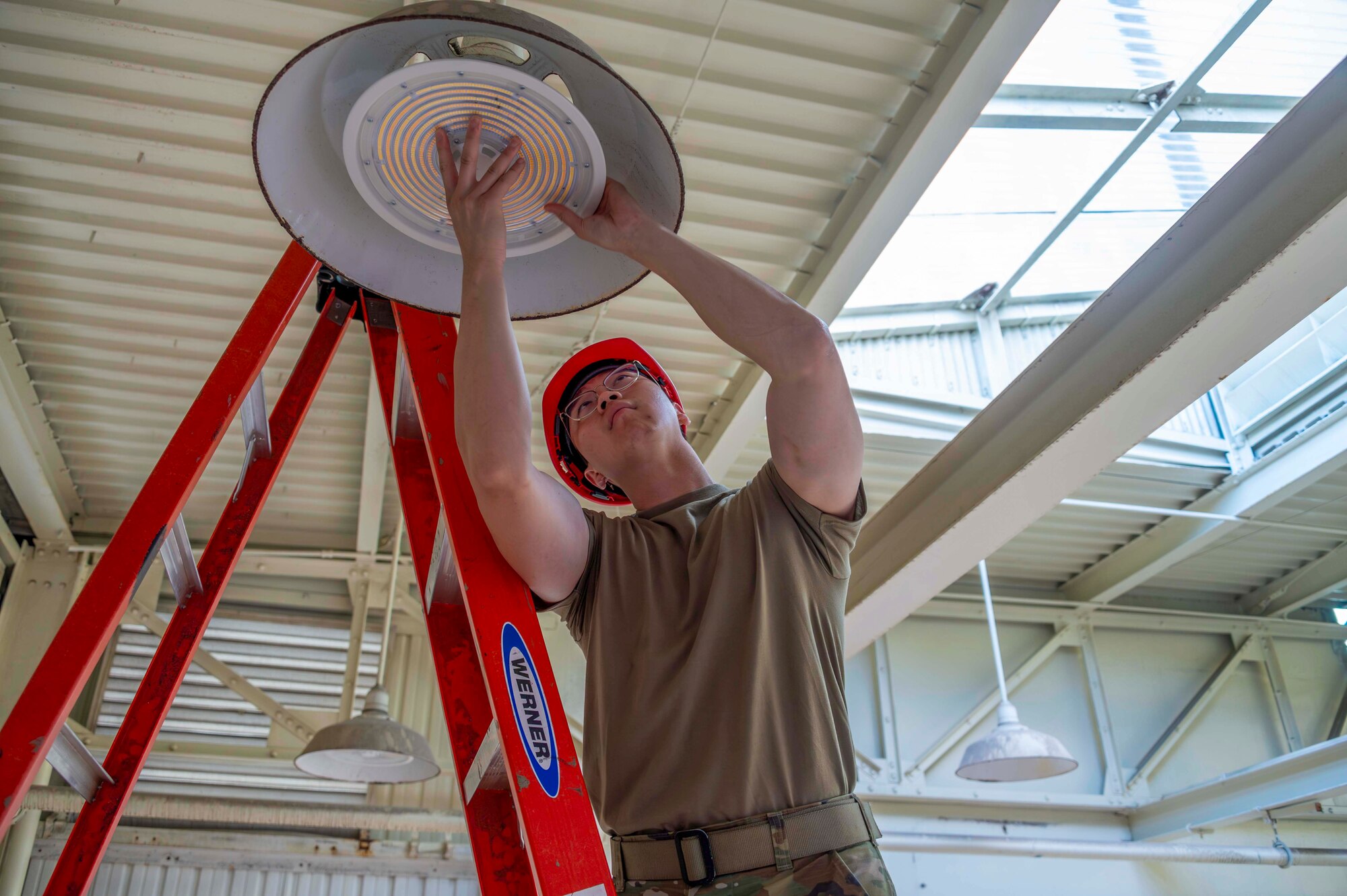 An Airman tightens a bulb on a light fixture during an Innovative Readiness Training