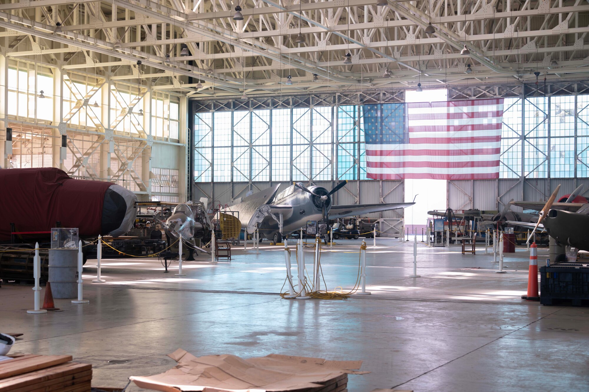 A WWII aircraft is displayed in front of an American flag in the Pacific Aviation Museum on Ford Island