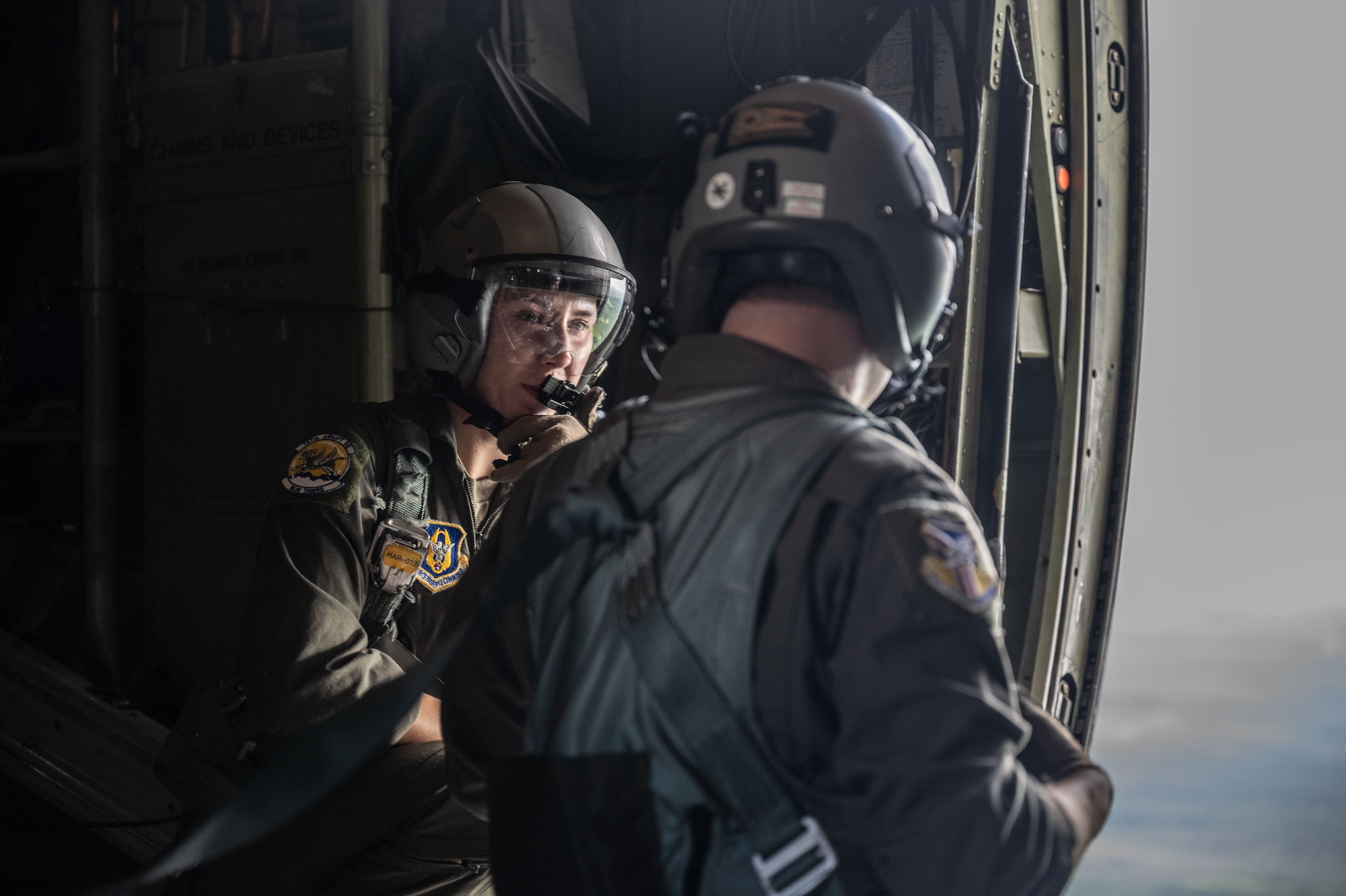 Two Airmen prepare to jump out of an aircraft.