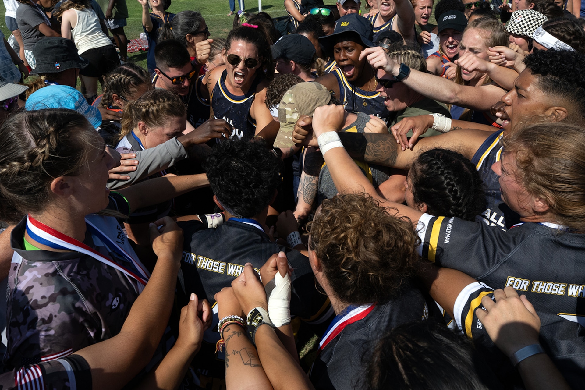 Wearing a pink ribbon in her hair, Navy Ensign Megan Neyen  leads a huddle of rugby players from all services in a cheer  ‘For Those Who Can’t’ at the conclusion of the 2024 Armed Forces Women’s Rugby Championships in San Diego, Calif. July 13, 2024. Team Army wore the motto “For Those Who Can’t’ on their uniforms to honor injured or deceased female service members. (DoD photo by EJ Hersom)