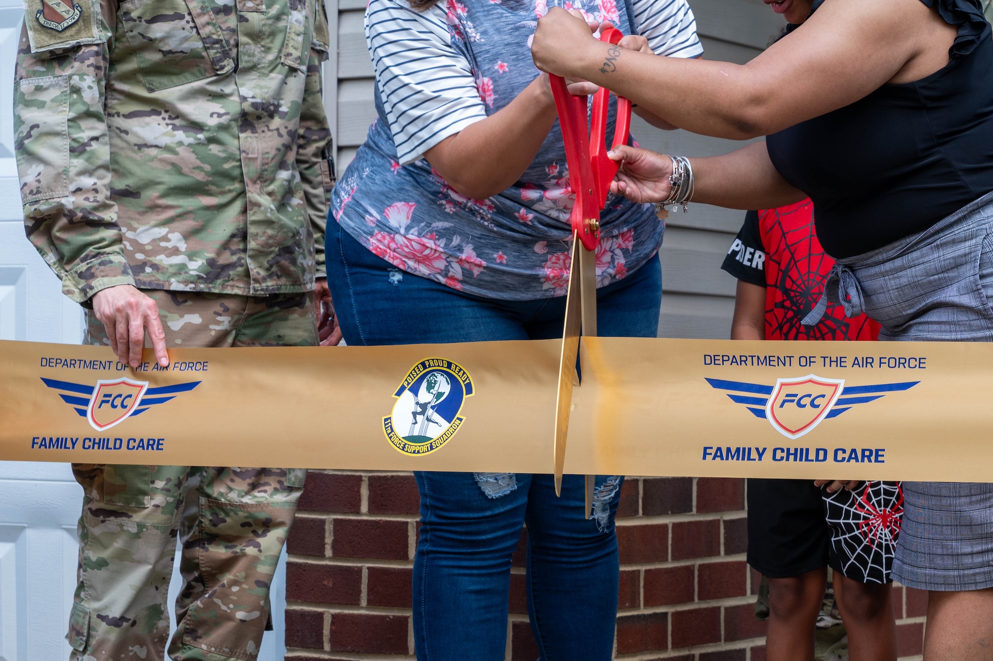 Krista Cox, a Family Child Care provider, and Aleicia Charlton, the acting community childcare coordinator for the Family Child Care program, 11th Flight Support Squadron, cut a ribbon opening the newest Family Child Care home at Joint Base Anacostia-Bolling, Washington, D.C., July 10, 2024. Cox has been in the military community for 14 years and is the newest provider to open their home to the FCC. (U.S. Air Force photo by Hayden Hallman)