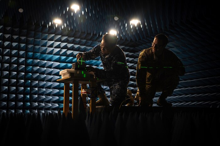 Two men work in a room designed to rest sound and radio waves.