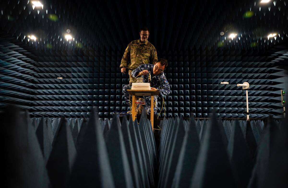 Two men work in a room designed to rest sound and radio waves.