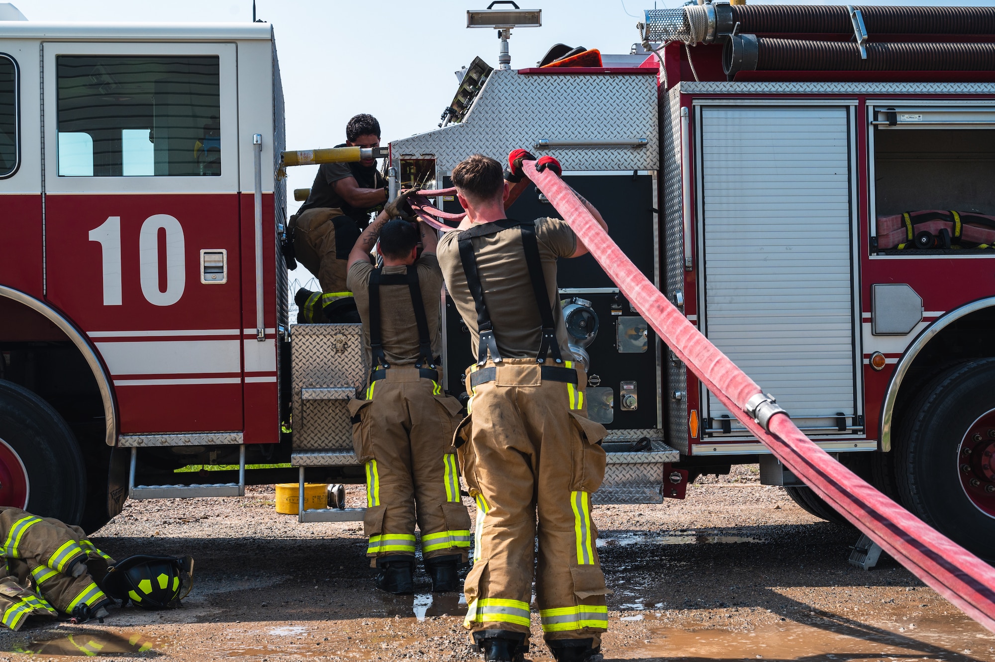From left, U.S. Air Force Staff Sgt. Mitchell Matthew, 8th Civil Engineer Squadron firefighter, Airman Scott Gales, 8th CES firefighter, and Senior Airman Dylan Antonson, 8th CES driver operator, load a hose into a firetruck.