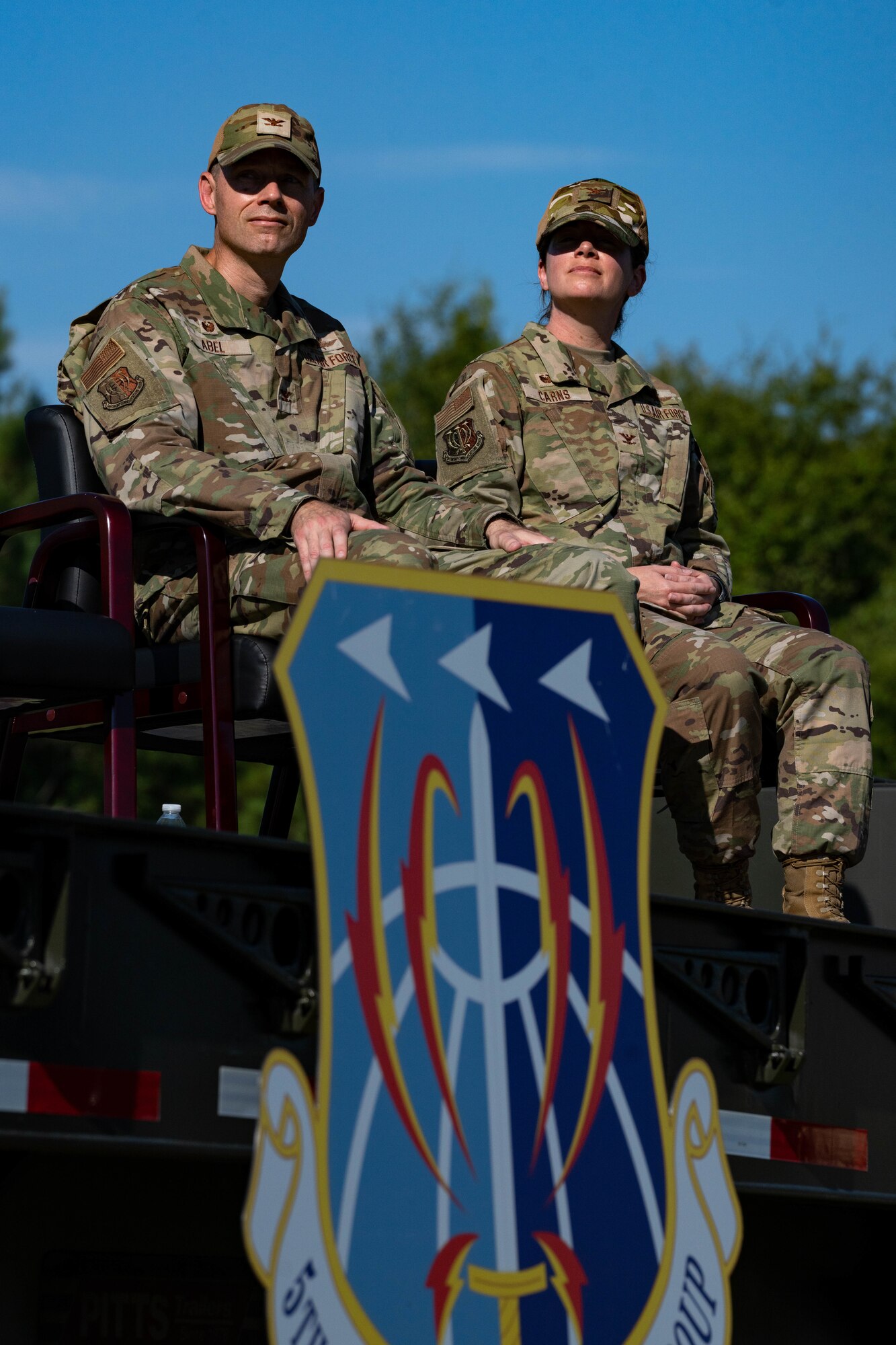 Two people in military uniform are sitting on stage