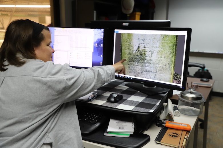 Carey Baxter, a CERL research archeologist, points to an illegible headstone in need of restoration
