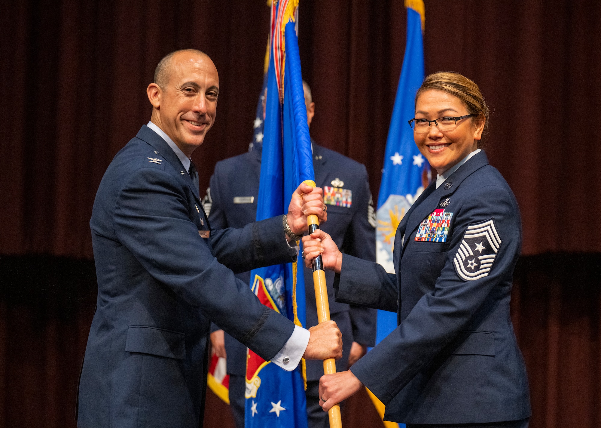 Chief Master Sgt. Bridget Bruhn accepts the Thomas N. Barnes Center for Enlisted Education guidon from Col. Damian Schlussel, commander, to become the Barnes Center command chief during a change of responsibility ceremony on Maxwell Air Force Base, Gunter Annex, Alabama, July 12, 2024. (U.S. Air Force photo/Brian Ferguson)