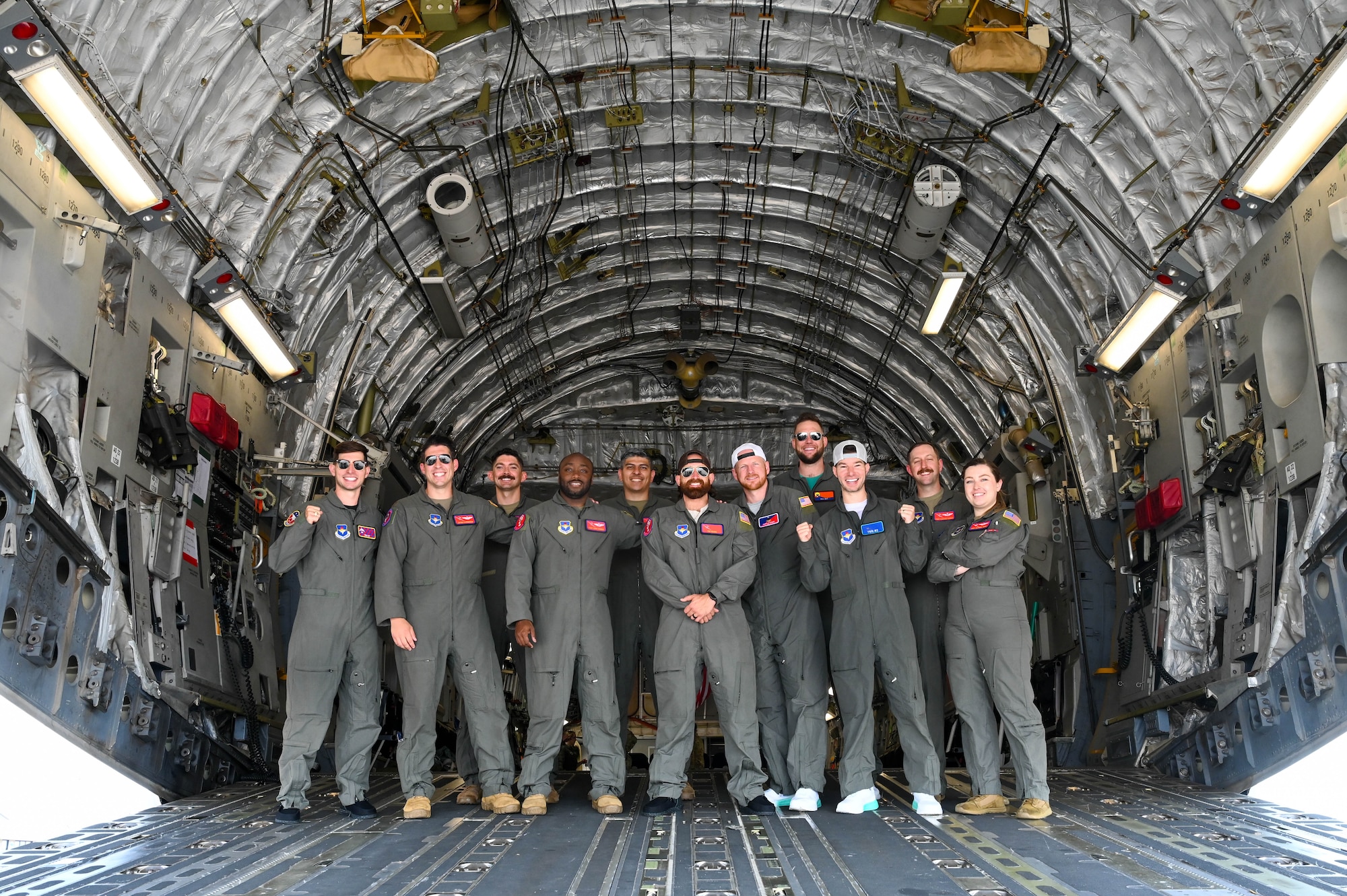 An aircrew from the 58th Airlift Squadron poses for a photo with the cast of Dude Perfect in a C-17 Globemaster III aircraft at Altus Air Force Base, Oklahoma, June 12, 2024. The aircrew executed the planning and mission for the Dude Perfect episode featuring the Airmen of the 97th Air Mobility Wing. (U.S. Air Force photo by Senior Airman Trenton Jancze)