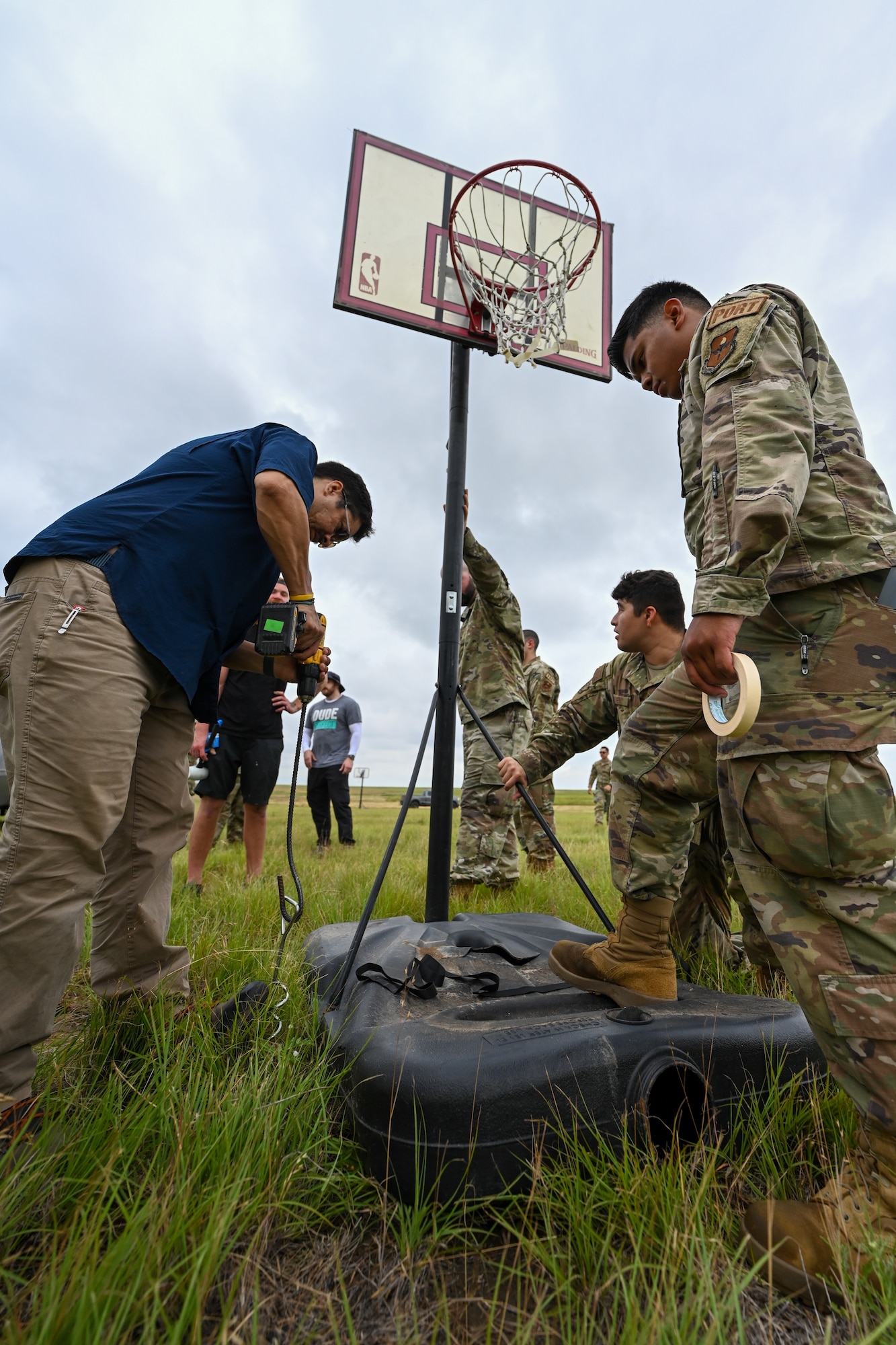 Airmen from the 97th Air Mobility Wing help the Dude Perfect film crew set up at Sooner Drop Zone, Oklahoma, June 11, 2024. In total, 47 basketball hoops were arranged on the drop zone in hopes of catching one of 1,000 basketballs dropped from a C-17 Globemaster III aircraft. (U.S. Air Force photo by Airman Lauren Torres)