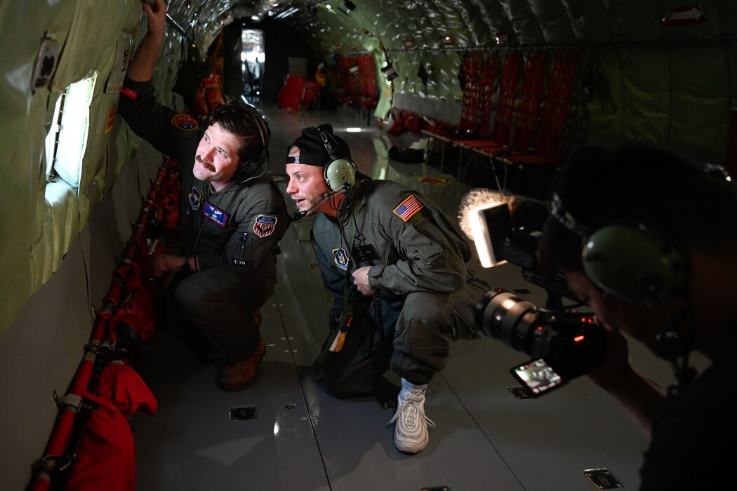 U.S. Air Force Tech. Sgt. Brandon Wright (left), 54th Air Refueling Squadron (ARS) instructor boom operator, and Sparky (right), Dude Perfect member, look out a window of a KC-135 Stratotanker aircraft at Altus Air Force Base, Oklahoma, June 12, 2024. During the “Dude Perfect” visit, the Airmen of the 54th ARS and the 58th Airlift Squadron showcased the air refueling capabilities between the KC-135 and the C-17 Globemaster III aircraft. (U.S. Air Force photo by Airman 1st Class Jonah Bliss)