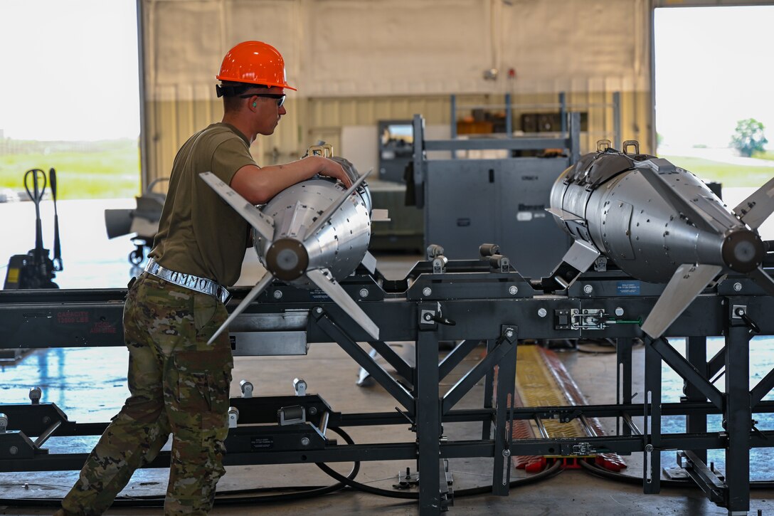 U.S. Air Force Staff Sgt. Logan Schafer, 28th Munitions Squadron conventional maintenance supervisor, guides a GBU-31 munition down a conveyer belt during a Combat Ammunition Production Exercise at Ellsworth Air Force Base, S.D., July 9, 2024. CAPEX is a non-aircraft, mass, live-munitions production exercise in support of air tasking orders, which provides an opportunity to evaluate munitions combat readiness. (U.S. Air Force photo by Staff Sgt. Jake Jacobsen)