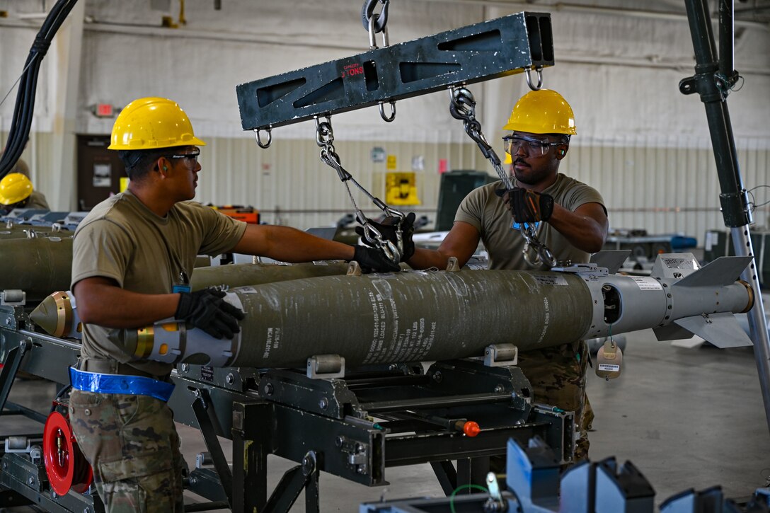 U.S. Air Force Senior Airman Jayohn Lee (right), and Airman 1st Class Fabian Laguna Granados (left), 9th Munitions Squadron equipment maintenance technicians, transport GBU-38 munitions to a conveyer during a Combat Ammunition Production Exercise at Ellsworth Air Force Base, S.D., July 9, 2024. CAPEX heavily emphasizes readiness, ensuring that Airmen and partners possess the knowledge, skills, and experience to rapidly build, transport and deploy munitions in the event of wartime operations. (U.S. Air Force photo by Staff Sgt. Jake Jacobsen)