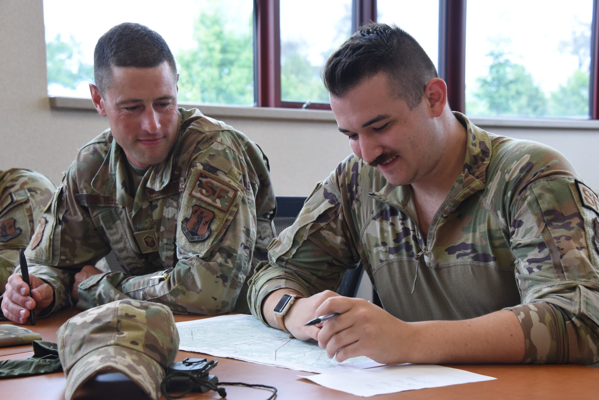 Master Sgt. Andy Walters, a 132nd Wing Security Forces Flight Chief, left, and Senior Airman Justin Dobek, 132nd Security Forces, right, work on land navigation in a classroom