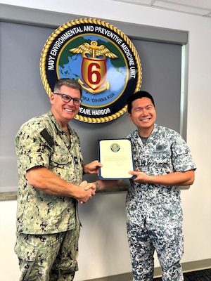 Capt. Scott Dunn, officer in charge of Navy Environmental and Preventive Medicine Unit Six (NEPMU-6), presents a Letter of Appreciation to Lt. Col. (DR.) Goh Jit Khong, a service member with the Singapore Armed Forces Force Health Group following a knowledge exchange between the two units during RIMPAC 2024, July 10, 2024 on Ford Island, Joint Base Pearl Harbor-Hickam. The Force Health Group was seeking guidance on the U.S. Navy’s expeditionary medical platforms, specifically the Forward Deployable Preventive Medicine Unit (FDPMU), in the hopes to establish a similar platform in their reserve component of the armed forces. (Navy photo by Senior Chief Hospital Corpsman Marsha Rivera)