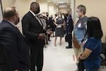 men and women wearing masks talk in a hallway