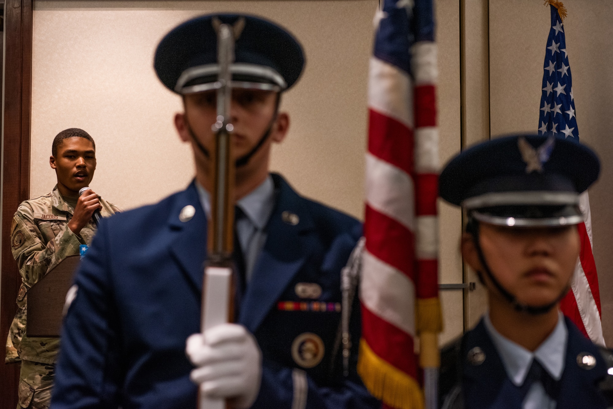 Airman singing the National Anthem with the honor guard in the foreground