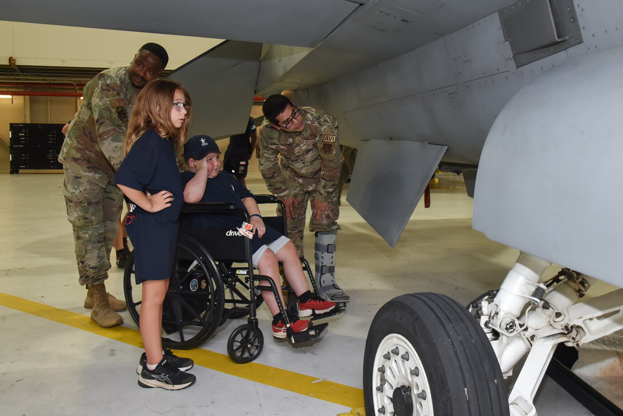 Children in front of an f-16 with Airmen.