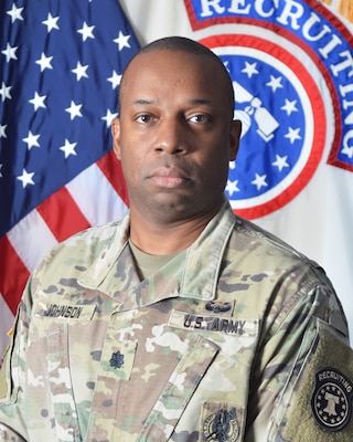 Army Soldier in uniform in front of American flag and USAREC flag