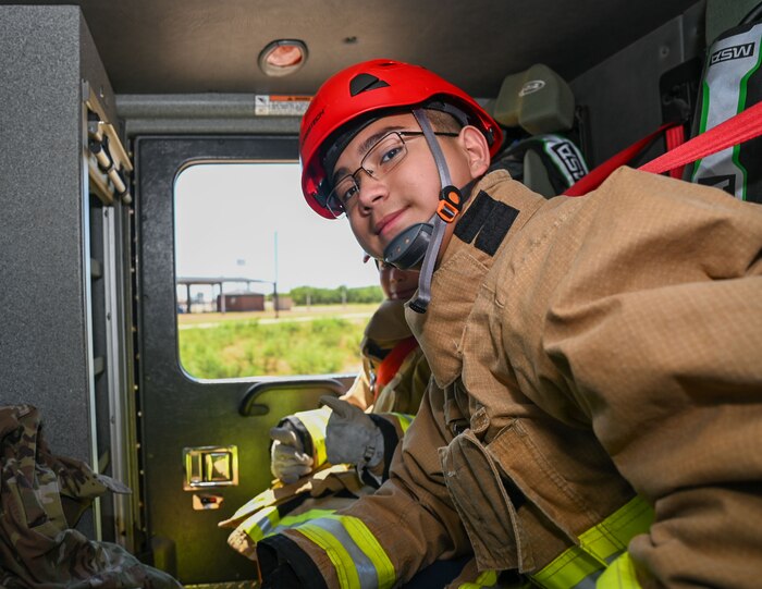Romeo, 12, sits in the back of a fire truck during the fourth day of the 2024 Junior Firefighter Camp at the Goodfellow Fire Department, Goodfellow Air Force Base, Texas, July 11, 2024. Students participated in a building search and rescue activity after the firetruck ride. (U.S. Air Force photo by Airman 1st Class Evelyn J. D’Errico)