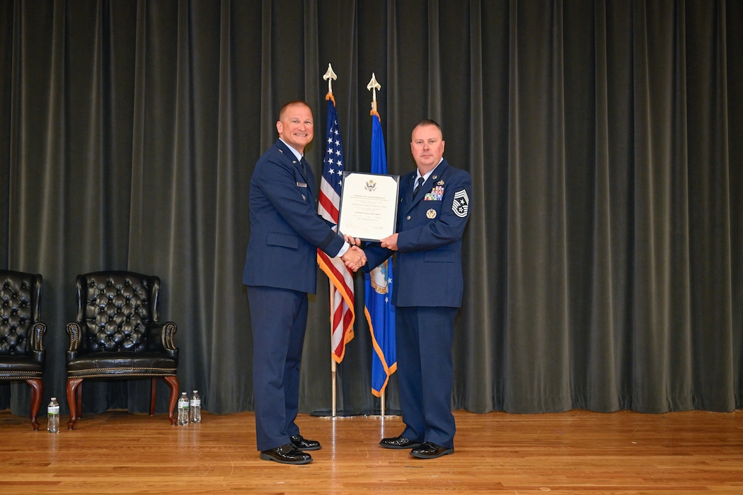 Two military men stand on stage.