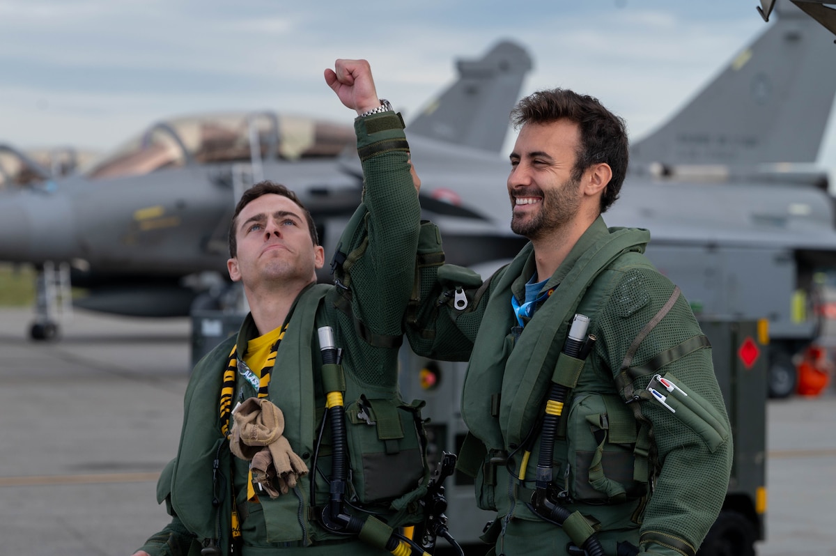 2 pilots from the Spanish Air Force walk off the flightline with a smile.